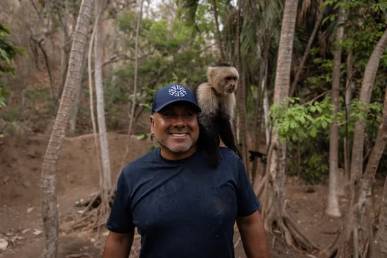 A visitor with a capuchin monkey on his shoulder near Playa Caldera, Costa Rica