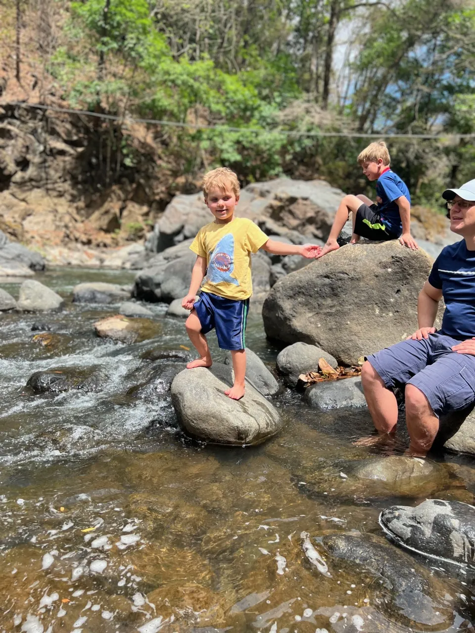 Family playing in a river and small waterfall in Costa Rica